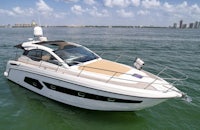 a white motor boat in the water with a city in the background