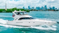 a white motor boat traveling on the water with a city in the background