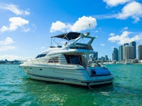 a white motor boat in the water with a city in the background