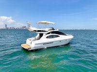 a white motor boat in the ocean with a city in the background