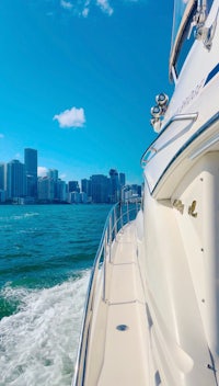 a white boat is traveling through the water with a city in the background