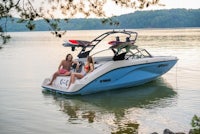 two people are sitting on a blue boat in the water