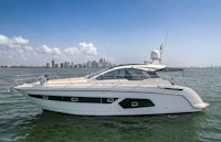 a white motor boat in the water with a city in the background