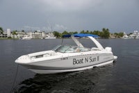 a white motor boat on the water with a boat in the background