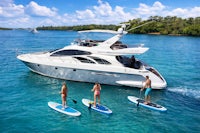 three people stand up paddle boarding on a yacht