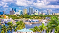 a city skyline with palm trees and boats on the water