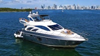a motor yacht in the water with a city skyline in the background