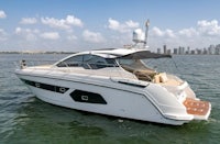 a white motor boat in the water with a city in the background